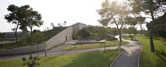 An angular stone building surrounded by trees and grass