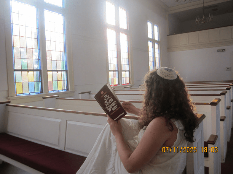 Emerson wearing her kippah, reading her book in a church. 