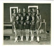 11 girls posed in two rows and smiling outside their bunkhouse
