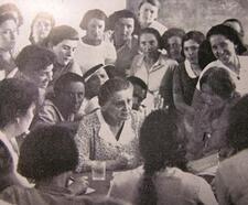 A large group of women crowded around a table, with Puah Rakovsky in the center