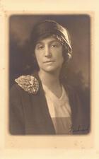 black and white photograph of a woman with a hat and a rosette on her shoulder