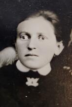 black and white historical photo of a woman in a black dress with a white collar