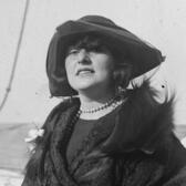 Cropped photo of Sally Milgrim outdoors, wearing a coat with a fur wrap and a hat