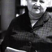 black and white photograph of an older woman with white hair holding a newspaper