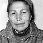 black and white phograph of a woman with a head covering looking stoically at the camera