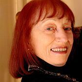 photgraph of a woman with red hair looking over her shoulder at the camera with a smile on her face