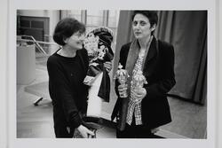 Miriam Rosengarten holding a Torah, partially removing its cover, and Rina Otterbach holding two Torah crowns