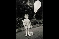 A young girl holding a flower purse and a balloon on a stick