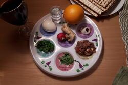 A seder plate with the six traditional items and an orange.
