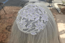 A white, lacy kippah worn on grey hair