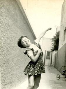 black and white photograph of a young girl in a shirt flowered dress dancing