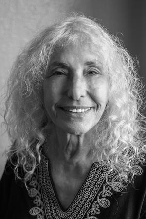 black and white photograph of a woman with long curly white hair smiling at the camera