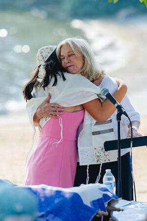 Aviva hugging her grandmother at her bat mitzvah, wearing her tallit