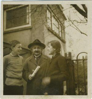 Black and white photograph of a man with a mustache and a hat looking at the camera, with a girl on one side and a boy on the other looking at him