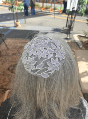 A white, lacy kippah worn on grey hair