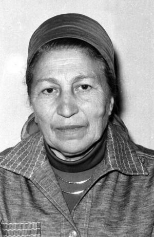 black and white phograph of a woman with a head covering looking stoically at the camera
