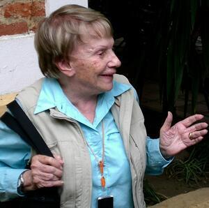 photograph of a woman with short blond hair talking with her hands, looking to the side