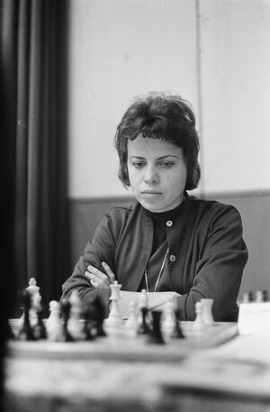 black and white photograph of a woman with short dark hair playing chess
