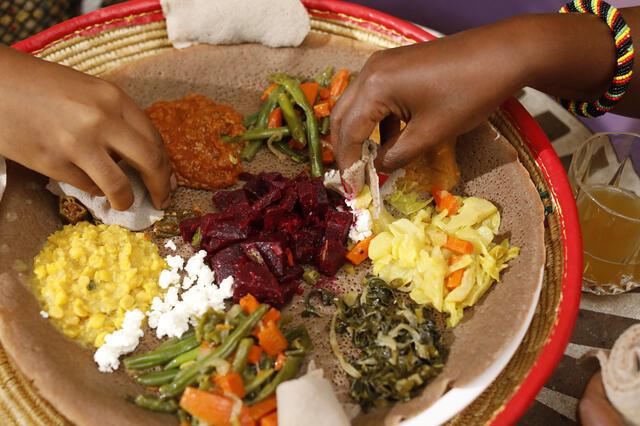 Hands reaching for spread of Ethiopian food