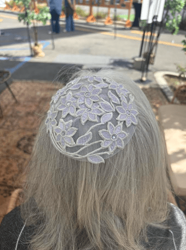 A white, lacy kippah worn on grey hair