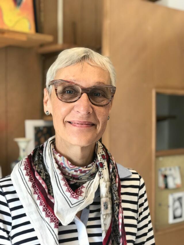 Doris Gray Headshot - Woman with short white hair, glasses, striped shirt