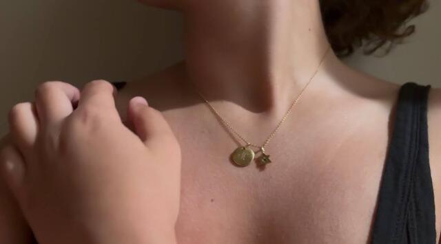Photo of person wearing a Star of David necklace and the letter M